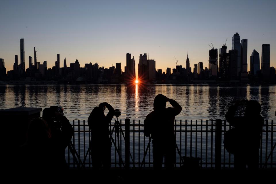 People view a Manhattanhenge sunrise along 42nd street in New York's Manhattan borough on Sunday, Nov. 29, 2020, as viewed from Weehawken, N.J. Manhattanhenge is when the rising sun intersects with the Manhattan street grid.
