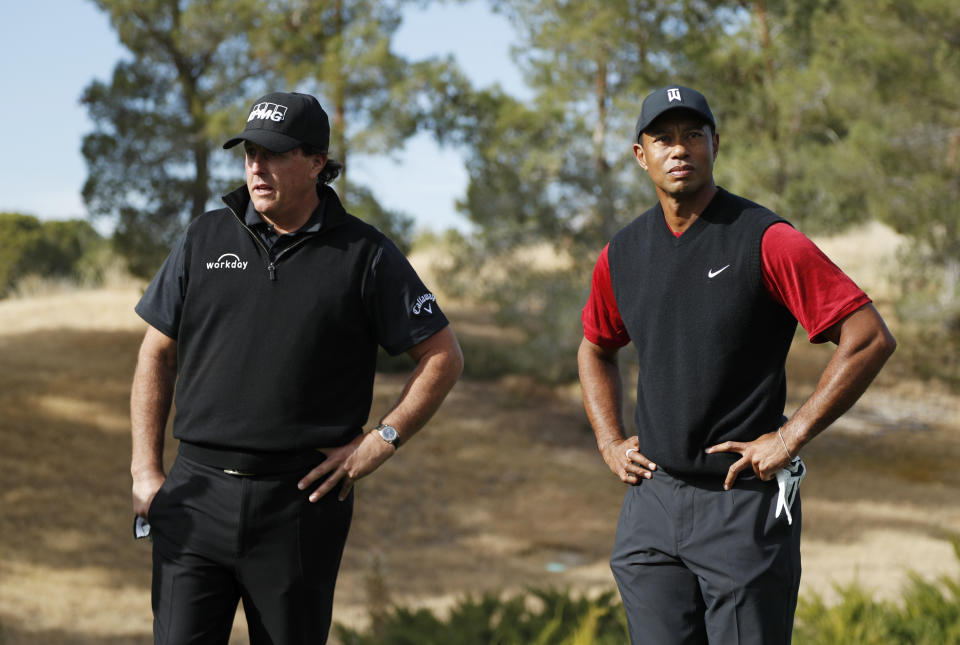 FILE - Phil Mickelson, left, and Tiger Woods stand at the first tee before a golf match at Shadow Creek golf course, Friday, Nov. 23, 2018, in Las Vegas. So much for peace and harmony in the world of golf. Jon Rahm's shocking defection from the PGA Tour to LIV again raises questions about where a pseudo-merger is headed, and whether both tours can possibly co-exist. (AP Photo/John Locher, File)