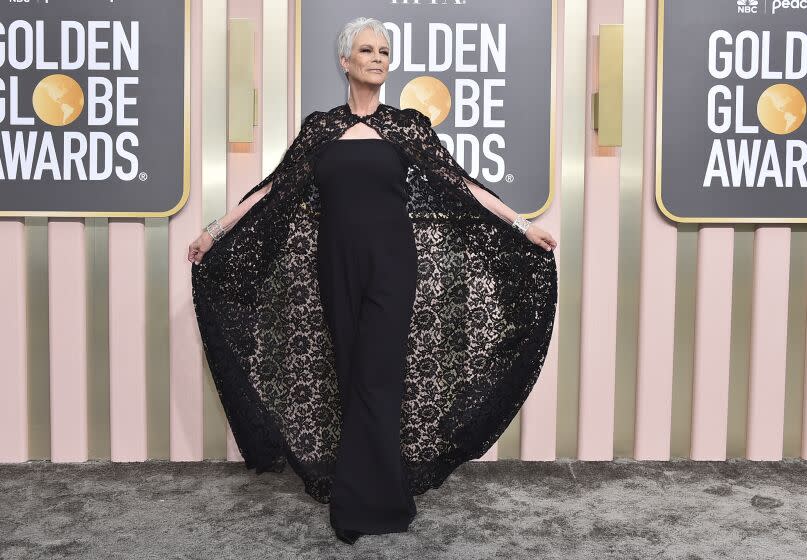 A woman in posed with her black lace cape on a gray carpet