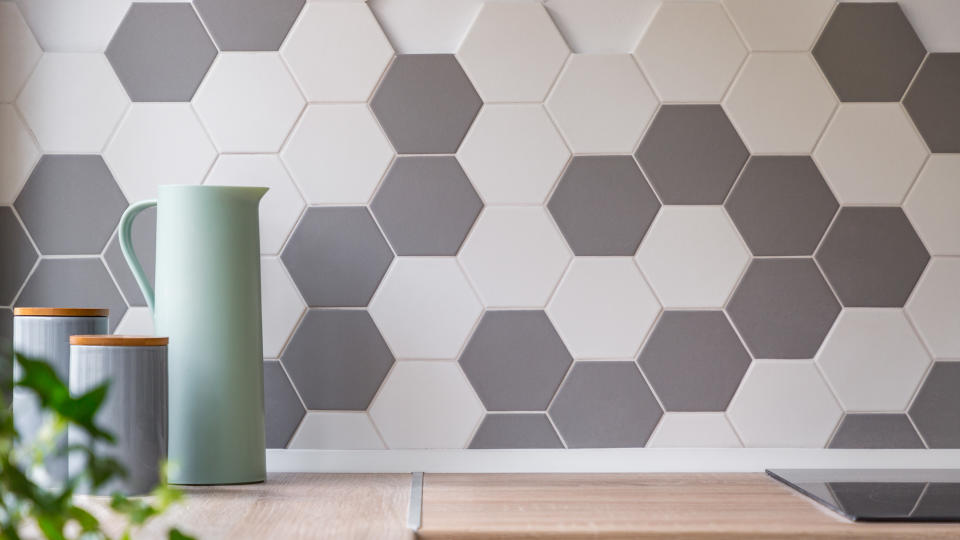 Kitchen with honeycomb wall tiles and wooden worktop.