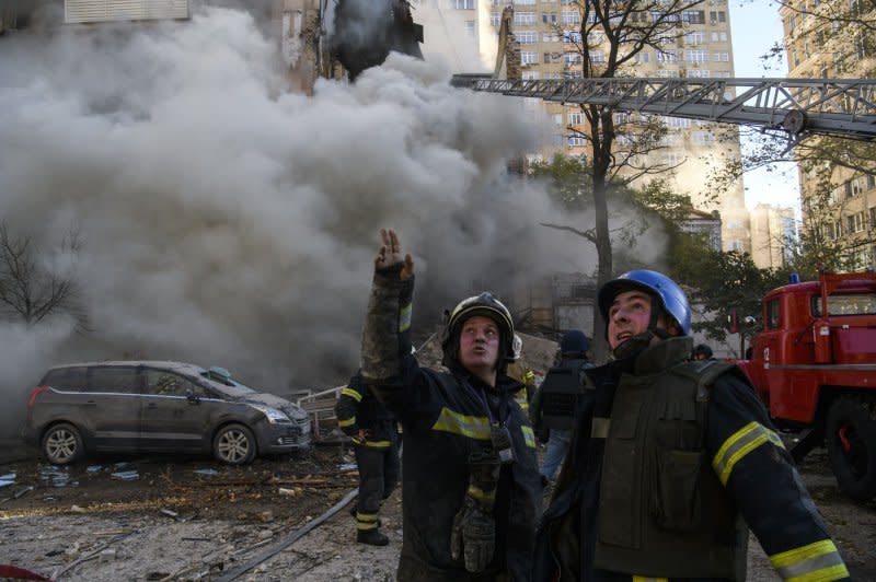 Firefighters conduct work while Smoke rises from a building after it was attacked by Russian suicide drones in Kyiv, Ukraine, Oct. 17, 2022. A study published Friday said the war has generated significant greenhouse gas emissions. File Photo by Vladyslav Musiienko /UPI