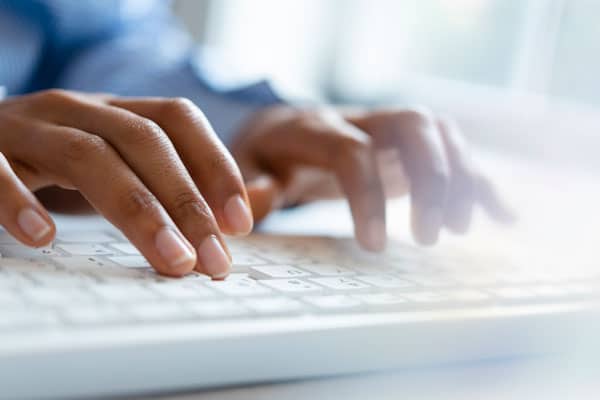 Hands of young woman typing on computer keyboard