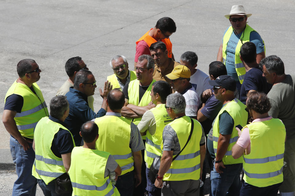 Tanker truck drivers on strike gather to listen to a workers union spokesman outside a fuel depot in Aveiras, outside Lisbon, Tuesday, Aug. 13, 2019. Soldiers and police officers are driving tanker trucks to distribute gas in Portugal as an open-ended truckers' strike over pay enters its second day. The government has issued an order allowing the army to be used. (AP Photo/Armando Franca)