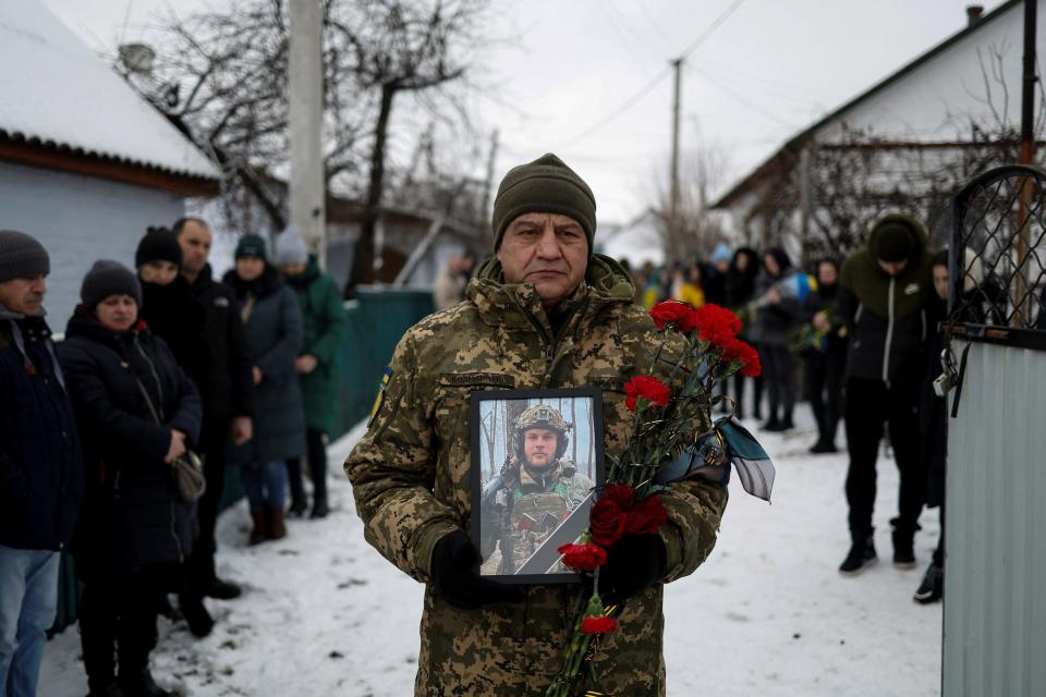 A Ukrainian serviceman holds a portrait of his brother-in-arms Volodymyr Androshchuk, who was recently killed in a fight against Russian troops near the Bakhmut town, during a funeral ceremony in the town of Letychiv, Khmelnytskyi region, Ukraine February 1, 2023.