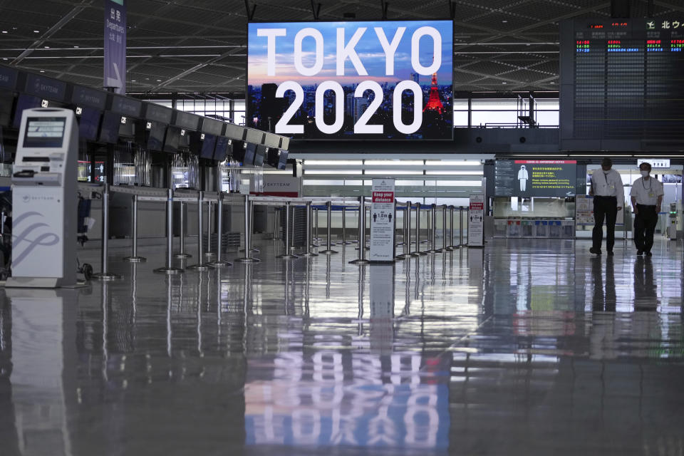 Staff wearing protective masks to help curb the spread of the coronavirus walk in the empty ticketing area at Narita International Airport Tuesday afternoon, June 1, 2021, in Narita, east of Tokyo. A state of emergency in Tokyo, Osaka and other prefectures was last week extended until June 20 as COVID-19 cases continue to put the medical system under strain. (AP Photo/Eugene Hoshiko)