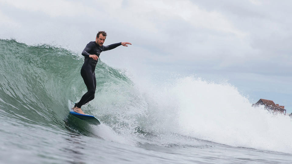 Person surfing/paddle boarding wearing wetsuit