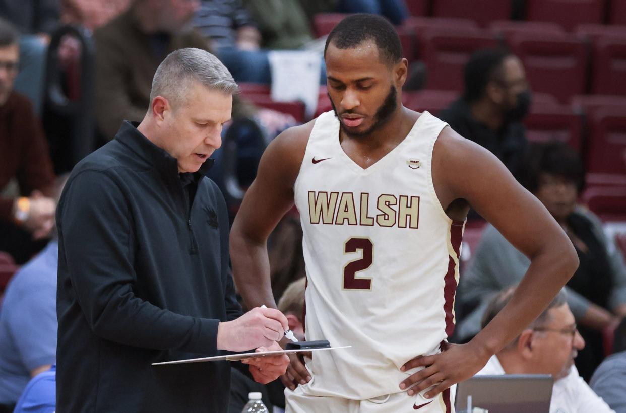 Walsh head coach Jeff Young draws up a play with Milan Square during a Great Midwest Athletic Conference Tournament game against Findlay last season.