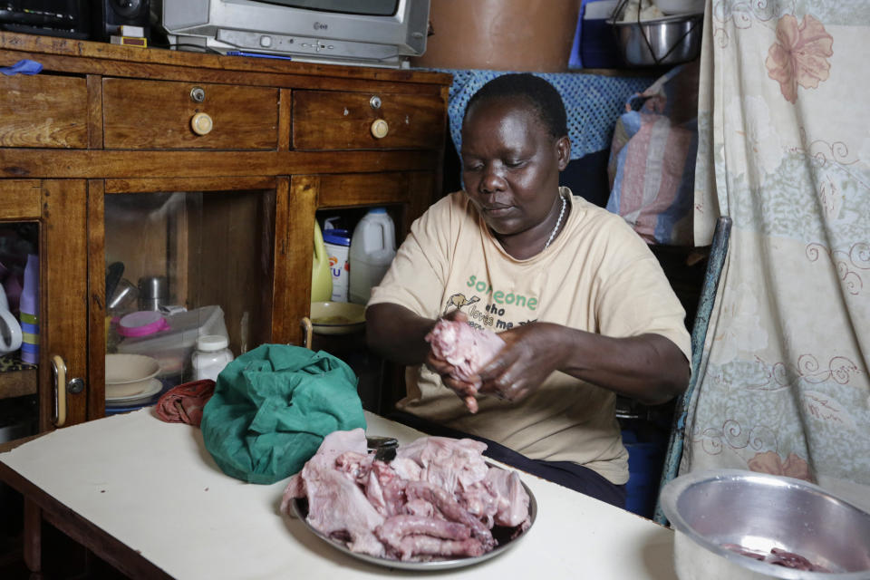 In this photo taken Thursday, June 4, 2020, Margaret Awino, 54, who lost her job after 15 years as a cleaner for a charity, prepares raw chicken that she bought to fry in the street to earn some income, in the Kibera slum, or informal settlement, of Nairobi, Kenya. Factories and stores are reopening and economies are reawakening but many jobs just aren't coming back - that's the harsh truth facing workers laid off because of the coronavirus around the U.S. and the world. (AP Photo/Khalil Senosi)