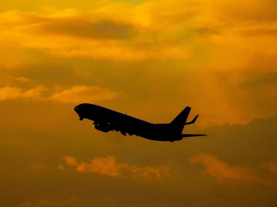 A flight takes off from Amsterdam Schiphol AMS EHAM International Airport in the Netherlands during sunset in 2021.