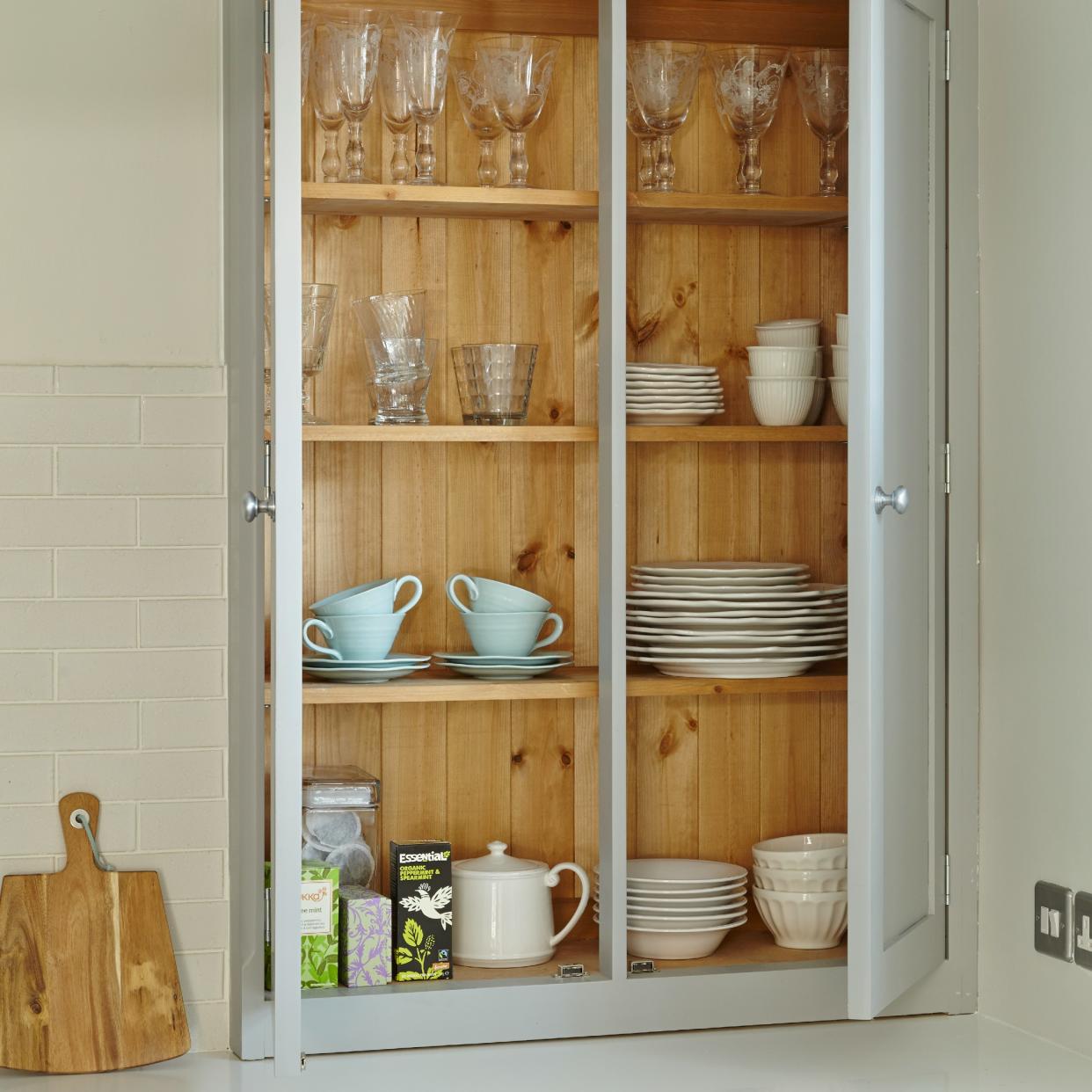  A kitchen cupboard filled with tableware and glassware. 
