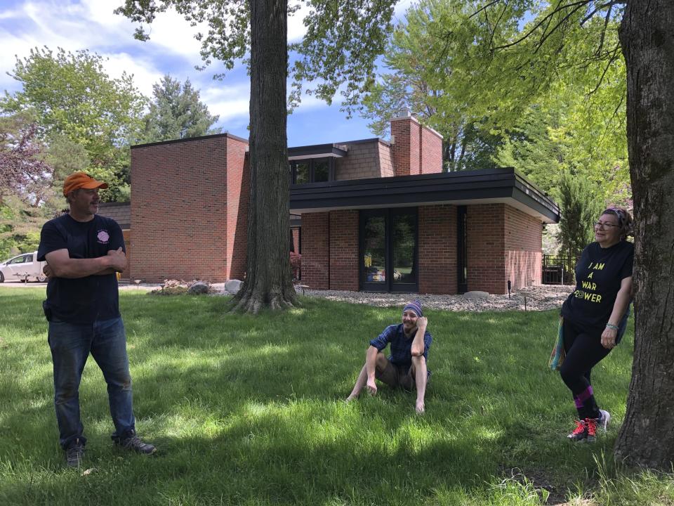 Charles Mikkelsen, left, his son Stewart Mikkelson and wife, Linda Mikkelsen take a break from cleaning up their 1966 midcentury modern home in Midland, Michigan, on Wednesday, May 27, 2020. Charles and Linda Mikkelsen moved to Midland from Dallas last November specifically because of the Central Michigan city's extensive midcentury architecture. Midcentury enthusiasts worry how many of the structures were damaged after torrential rains overwhelmed two dams and submerged much of the city. (AP Photo/Tammy Webber)