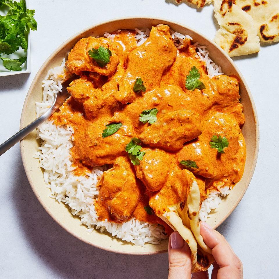 butter chicken in a bowl with rice topped with cilantro