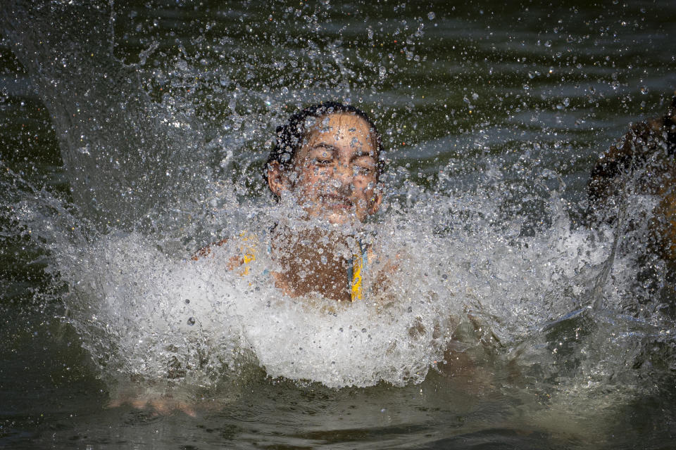 A girls splashes water while cooling off in the river Arges, outside Bucharest, Romania, Wednesday, July 12, 2023. Weather services issued a heat warning for the coming days in southern Romania, with temperatures expected to exceed 40 degrees Centigrade (104 Fahrenheit) in the shade. (AP Photo/Andreea Alexandru)