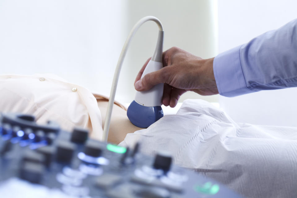 A technician performs an ultrasound scan on the abdomen of a patient