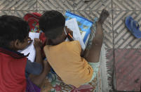 Children practice writing numbers during a sidewalk class taught by an Indian couple, Veena Gupta and her husband Virendra Gupta, in New Delhi, India, on, Sept. 3, 2020. It all began when Veena's maid complained that with schools shut, children in her impoverished community were running amok and wasting time. The street-side classes have grown as dozens of children showed keen interest. Now the Guptas, with help from their driver, teach three different groups three times a week, morning and evening. As most schools in India remain shut since late March when the country imposed a nationwide lockdown to curb the spread of COVID-19, many switched to digital learning and taking classes online. (AP Photo/Manish Swarup)