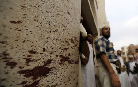 Members of the Ismaili community stand near a blood-stained wall at the site of a car bomb attack outside an Ismaili mosque in Yemen's capital Sanaa July 29, 2015. REUTERS/Khaled Abdullah