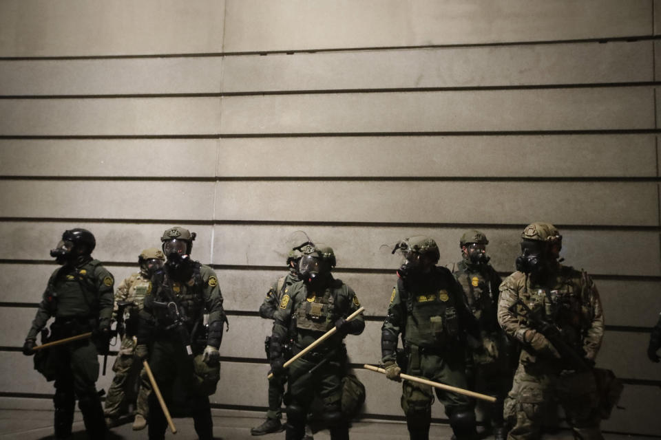 Federal agents watch demonstrators after an illegal assembly was declared during a Black Lives Matter protest at the Mark O. Hatfield United States Courthouse Wednesday, July 29, 2020, in Portland, Ore. (AP Photo/Marcio Jose Sanchez)