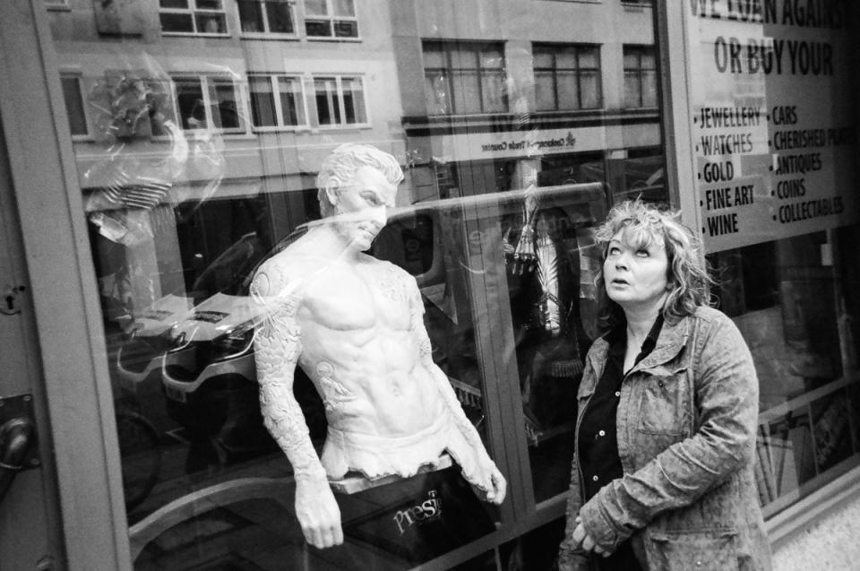 A mannequin stares at a woman as she walks past a London shop. (Cafe Art/SWNS)