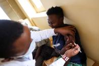 Woman reacts as a healthcare professional administers a dose of AstraZeneca (COVID-19) vaccine, in Talek