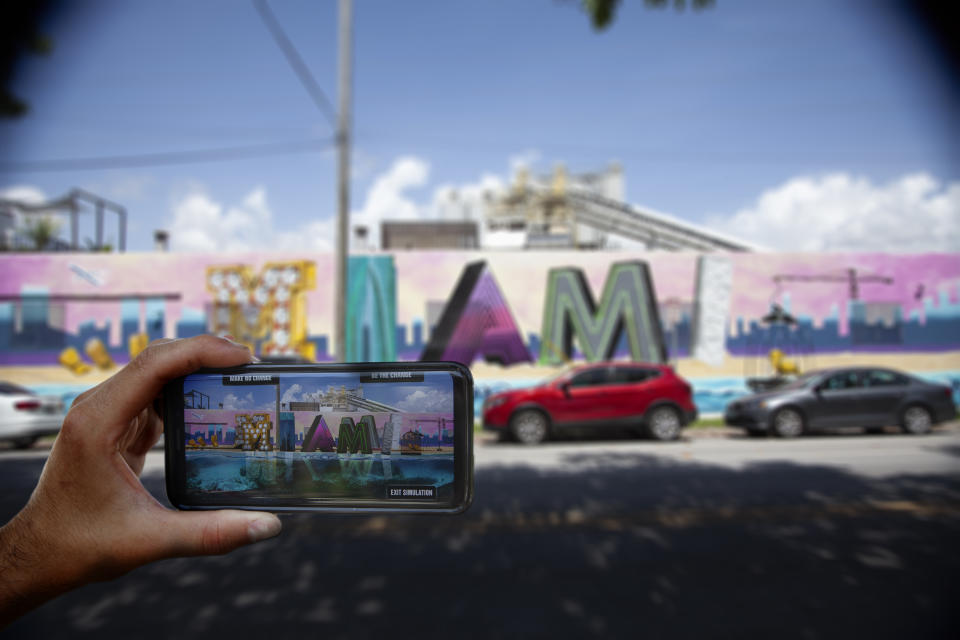 A viewer uses their smartphone to view &lsquo;What Future Do You Choose for Miami?&rsquo;, an augmented reality mural in the city. (Photo: Before Its Too Late)