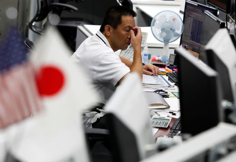 A dealer scratches his face at a foreign exchange trading company in Tokyo