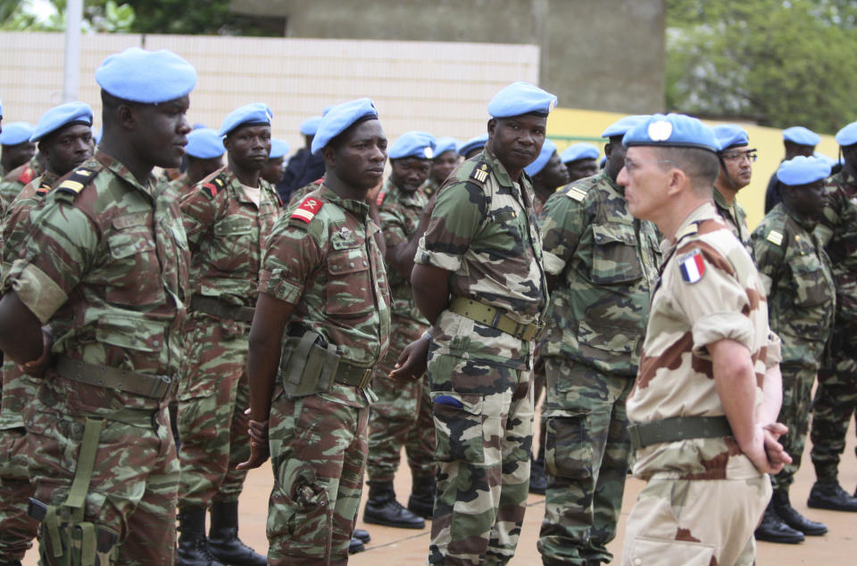 FILE- A French soldier stands alongside African troops, as they participate in a ceremony formally transforming the force into a United Nations peacekeeping mission, in Bamako, Mali, July 1, 2013. The roughly 6,000 African troops were folded into the Integrated United Nations Mission for the Stabilization of Mali, or MINUSMA. The pending pullout of U.N. peacekeepers from Mali is creating worries about what the withdrawal will mean for thousands of citizens who built livelihoods at and around the mission's bases. (AP Photo/Harouna Traore, file)