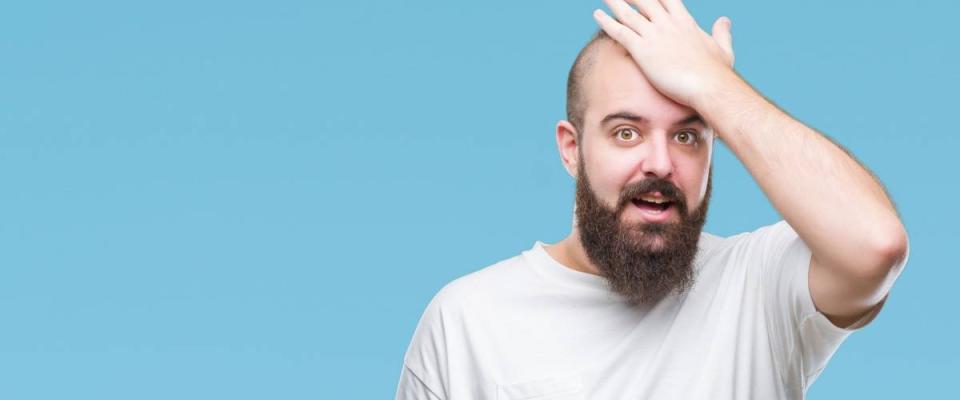 Young caucasian hipster man wearing casual t-shirt over isolated background surprised with hand on head for mistake, remember error. Forgot, bad memory concept.