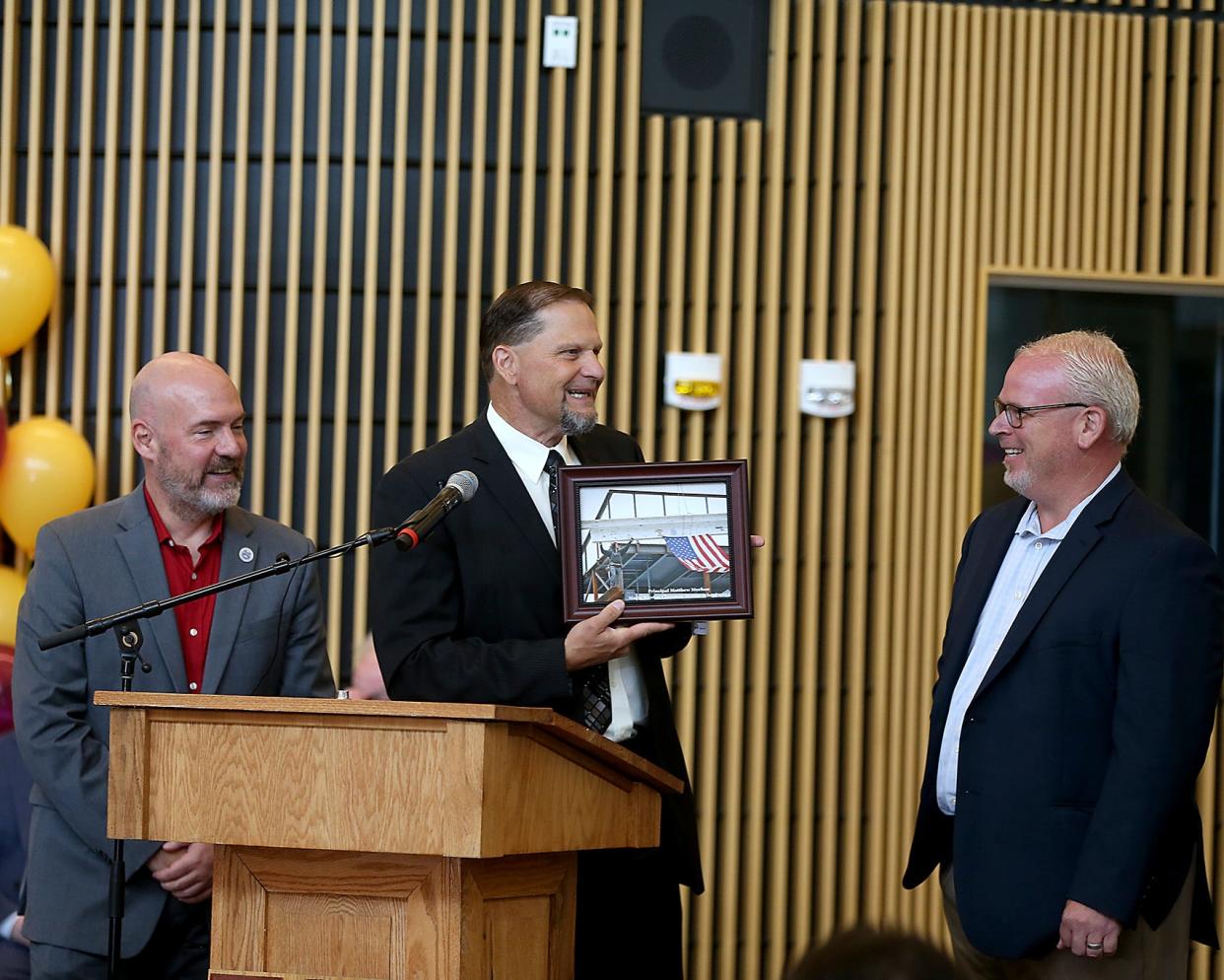 Mayor Bob Hedlund presents a gift to Chapman Middle School principal Matthew Meehan as Ted Langill, chief of staff for the mayor, looks on during ceremony for the new Chapman Middle School in Weymouth on Saturday, Aug. 6, 2022.