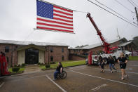 Attendees of the funeral services for Louisiana State Police Master Trooper Chris Hollingsworth, walk past a suspended American flag, Friday, Sept. 25, 2020, in West Monroe, La. Hollingsworth, killed in a car crash hours after he was told he would be fired for his role in the death of a Black man, was buried with honors Friday at a ceremony that authorities sought to keep secret out of concerns it would attract a mass protest. (AP Photo/Rogelio V. Solis)