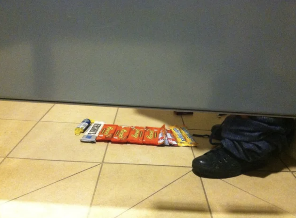 line of candy bars in front of feet in the bathroom stall