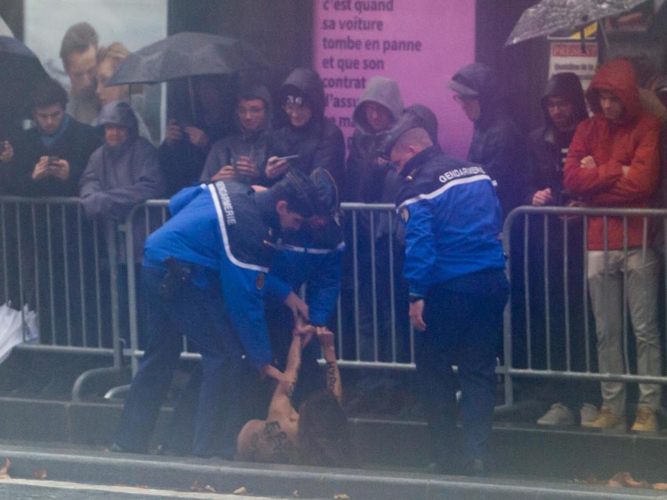 Police stop two topless female rights activists from approaching Trump's motorcade in Paris