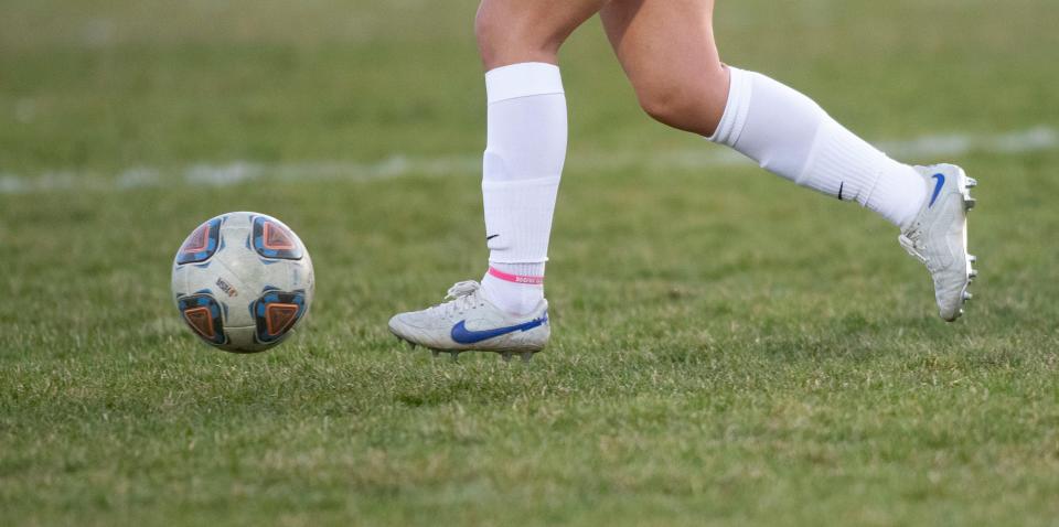 A girls soccer player kicks the ball.