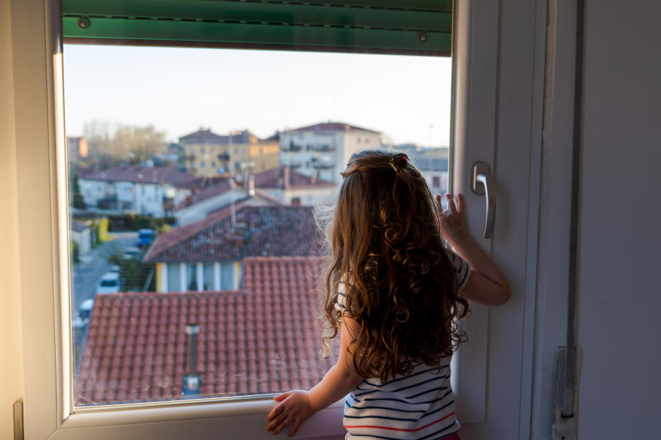 cute little girl spending time looking through the window after a week of quarantine for the cov 19 in italy