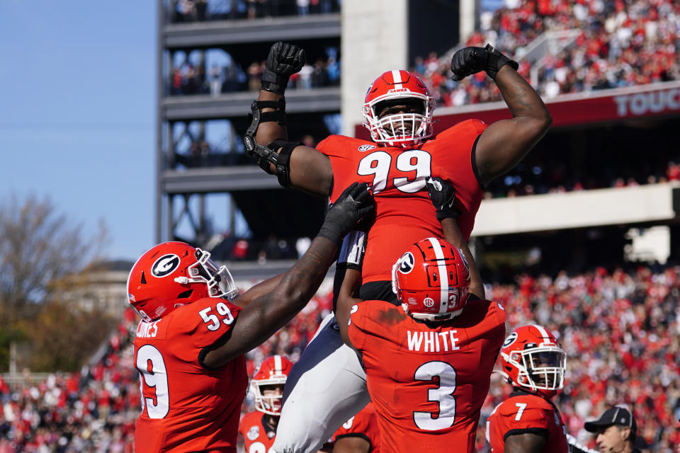 Georgia defensive lineman Jordan Davis (99) is lifted into the air by running back Zamir White (3) and offensive lineman Justin Shaffer (54) after scoring a touchdown in the first half of an NCAA college football game against Charleston Southern, Saturday, Nov. 20, 2021, in Athens, Ga.. (AP Photo/John Bazemore)