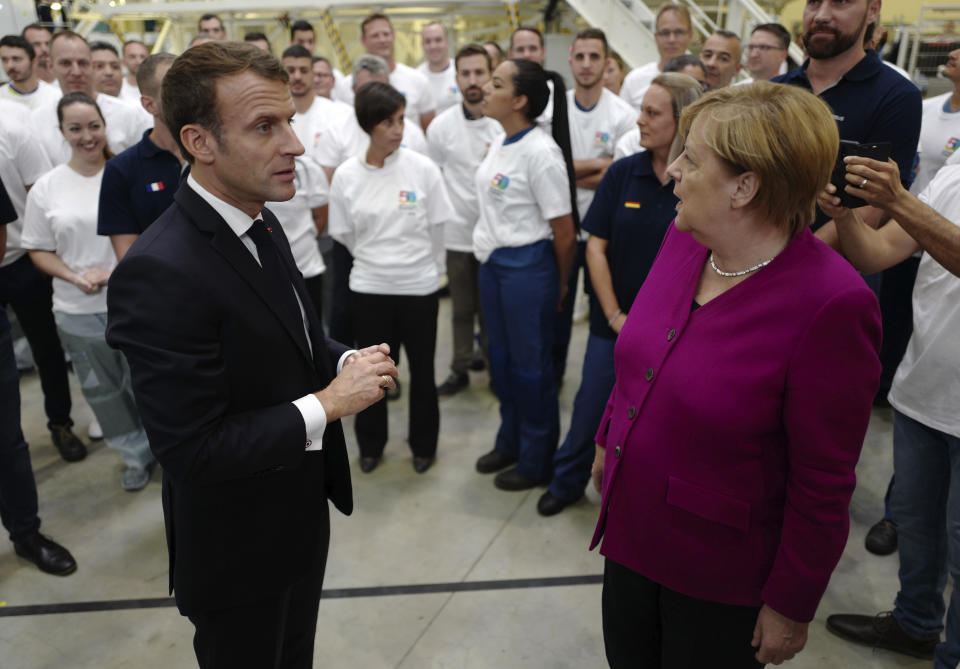 French President Emmanuel Macron and German Chancellor Angela Merkel react as they talk to Airbus French and German employees after visiting the assembly line of the Airbus A350 in Toulouse, southwestern France, Wednesday, Oct.16, 2019. French President Emmanuel Macron and German Chancellor Angela Merkel are meeting in southern France, one day before a key EU summit that may approve a divorce deal with Britain. (AP Photo/Frederic Scheiber, Pool)