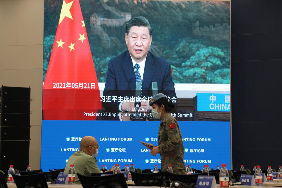 A Chinese United Nations peacekeeper chats with an attendee near a display showing Chinese President Xi Jinping before the start of a symposium to mark the 50th anniversary of the People's Republic of China's entry into the U.N. at the Foreign Ministry in Beijing on Friday, June 25, 2021. Foreign Minister Wang Yi said China remains deeply committed to United Nations peacekeeping efforts, where more than 2,400 Chinese troops and police are serving, a contribution that underscores China's increasing prominence in the world body. (AP Photo/Ng Han Guan)