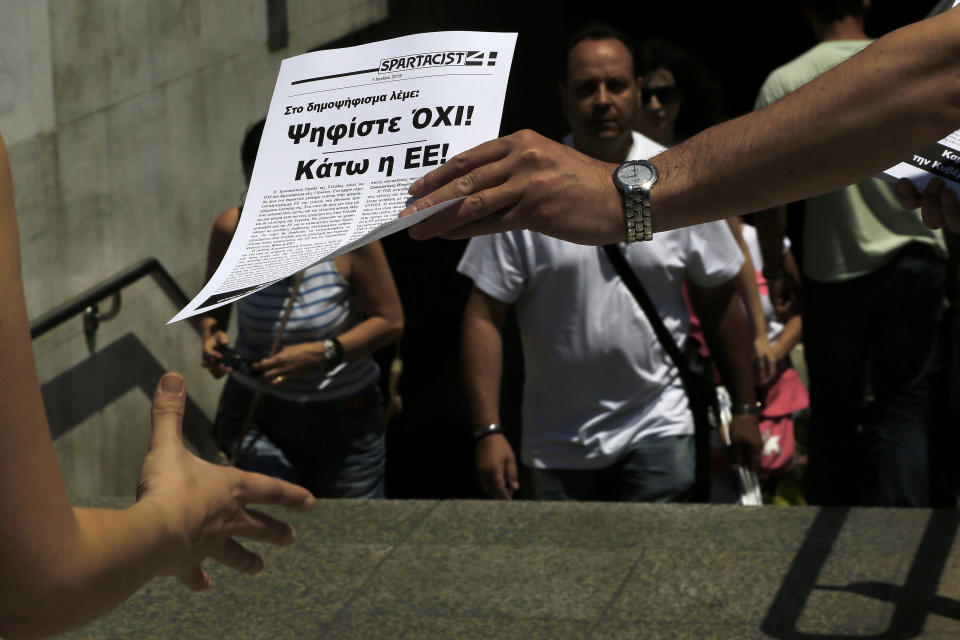 A man passes out a leaflet reading in Greek "Vote NO in the referendum, Down with the EU" in Athens, Greece, on July 2, 2015