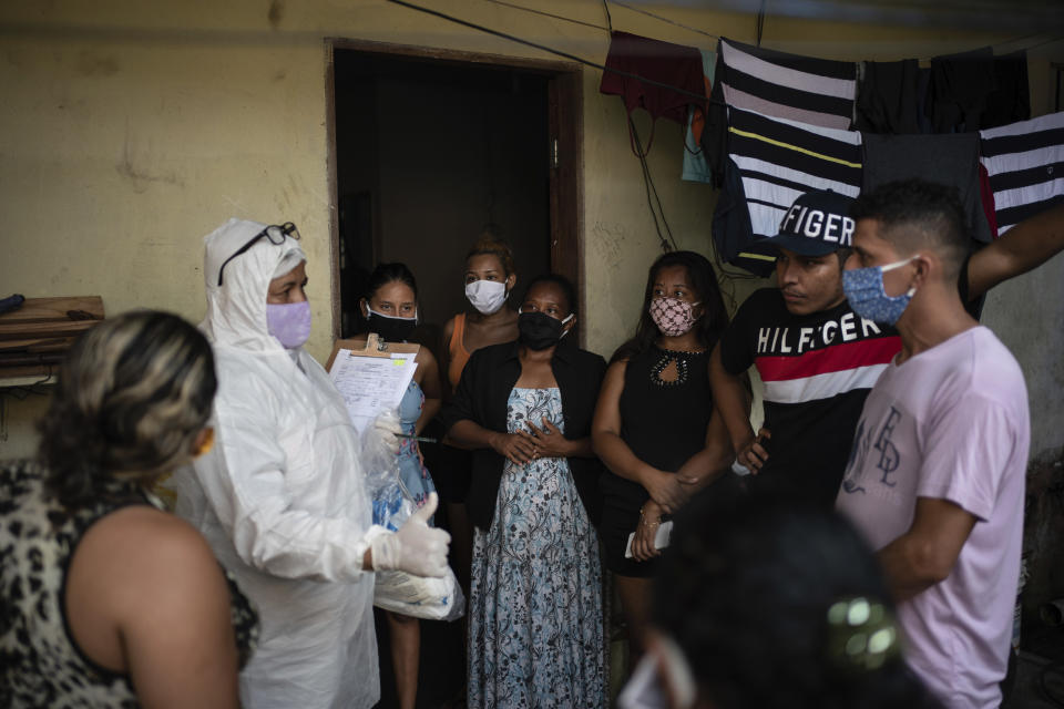 Familiares y amigos del fallecido Eldon Cascais hablan con un empleado de SOS Funeral, vestido con un traje de protección, durante la pandemia del coronavirus en Manaos, Brasil, el 9 de mayo de 2020. Según la familia, Cascais tenía cáncer de pulmón y murió en su casa tras sufrir problemas para respirar, tos y fartiga durante una semana. (AP Foto/Felipe Dana)