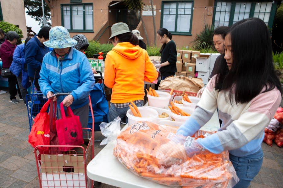 Volunteer Minh Thu Tran (right) bundles up carrots offered by SF-Marin Food Bank at the Richmond Neighborhood Center food pantry in San Francisco, Calif. (Photo by Santiago Mejia/San Francisco Chronicle via Getty Images)