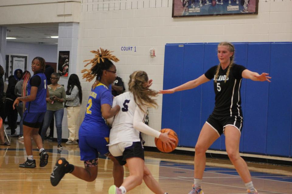 Calvary Day's Hannah Cail drives to the basket defended by Aaliyah Williams of Beach and Veronica Sierzant of Islands (No. 5 in black).