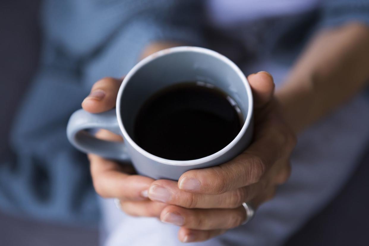 close up of woman holding coffee cup at home