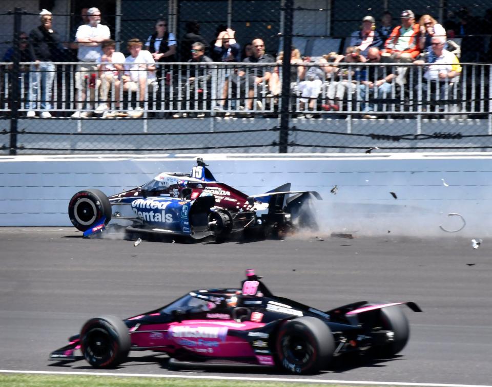 Meyer Shank Racing driver Helio Castroneves (6) drives low on the track to pass Rahal Letterman Lanigan Racing driver Graham Rahal (15) as he crashes in turn two after his rear left wheel comes loose Sunday, May 30, 2021, during the 105th running of the Indianapolis 500 at Indianapolis Motor Speedway.