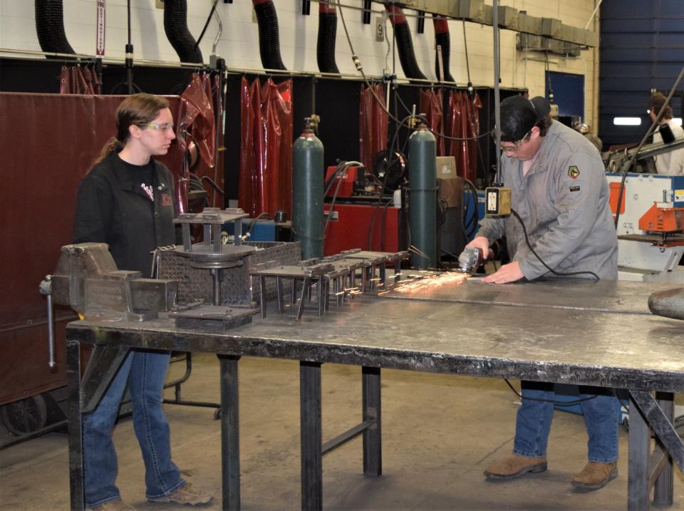 Trevor Harding preps a piece of steel he will be welding, as classmate Erica Calame awaits her turn during RAMTEC training at Ashland County West Holmes Career Center.