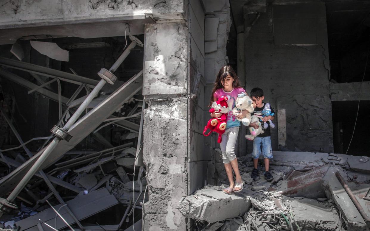 Palestinian children salvage toys from their home at the Al-Jawhara Tower in Gaza City - AFP