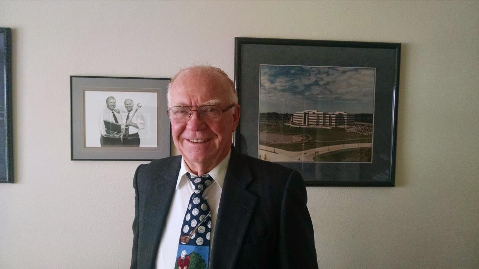 Wally Hilliard stands in from of photos of himself and long-time business partner Ron Weyers (left) and of the American Medical Security headquarters in Howard.