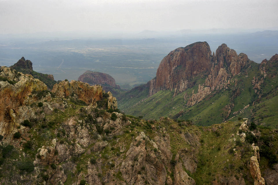 The rugged Baboquivari Mountains cut through the Sonoran Desert as seen from a US Customs and Border Protection helicopter, Thursday, Sept. 8, 2022, near Sasabe, Ariz. This desert region located in the Tucson sector is one of the deadliest stretches along the international border with rugged desert mountains, uneven topography, washes and triple-digit temperatures in the summer months. his section of the border consists of wall, bollards or no barrier at all and has become a corridor of choice for migrants who don't turn themselves in right after crossing or apply for protection legally. (AP Photo/Giovanna Dell'Orto)