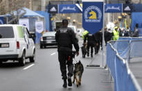 A law enforcement official patrols the area with a dog near the finish line of the Boston Marathon, Tuesday, April 15, 2014, in Boston. Vice President Joe Biden is expected to be among the dignitaries Tuesday during ceremonies to honor victims, and the first responders, doctors and nurses who helped them, following the April 15, 2013, bombings, during a tribute at the Hynes Convention Center in Boston. (AP Photo/Steven Senne)