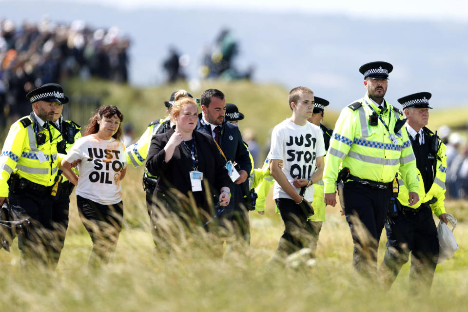Just Stop Oil protesters are led away by police and security, during the second day of the British Open Golf Championships at the Royal Liverpool Golf Club in Hoylake, England, Friday, July 21, 2023. (Richard Sellers/PA via AP)