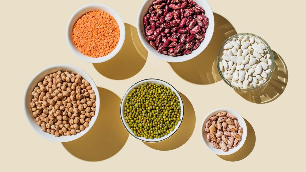 various kinds of vegan protein sources on beige background nuts and legumes green mung beans, chick pea, red lentil, kidney bean, almonds, hazelnuts flat lay, top view