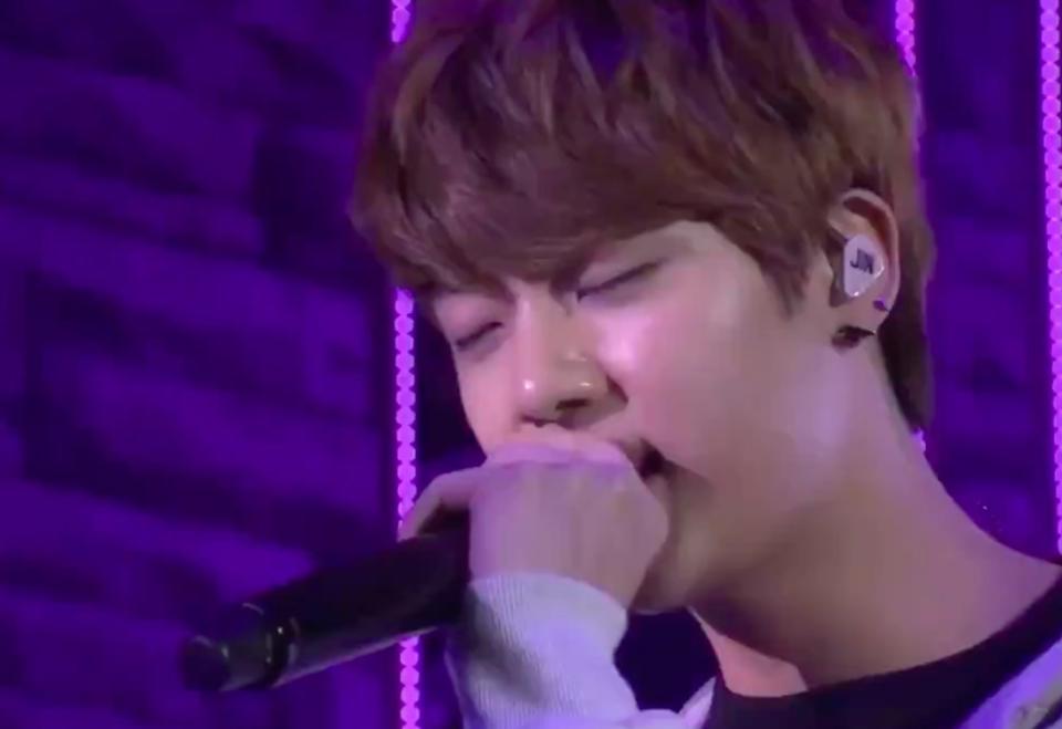 Jin closes his eyes while singing into a microphone